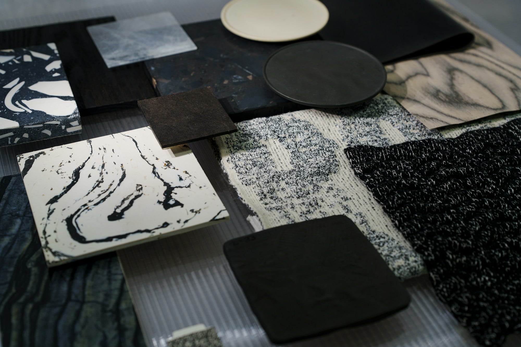 Close-up of interior material samples including stone, tweed and leather swatches in charcoal and ivory tones