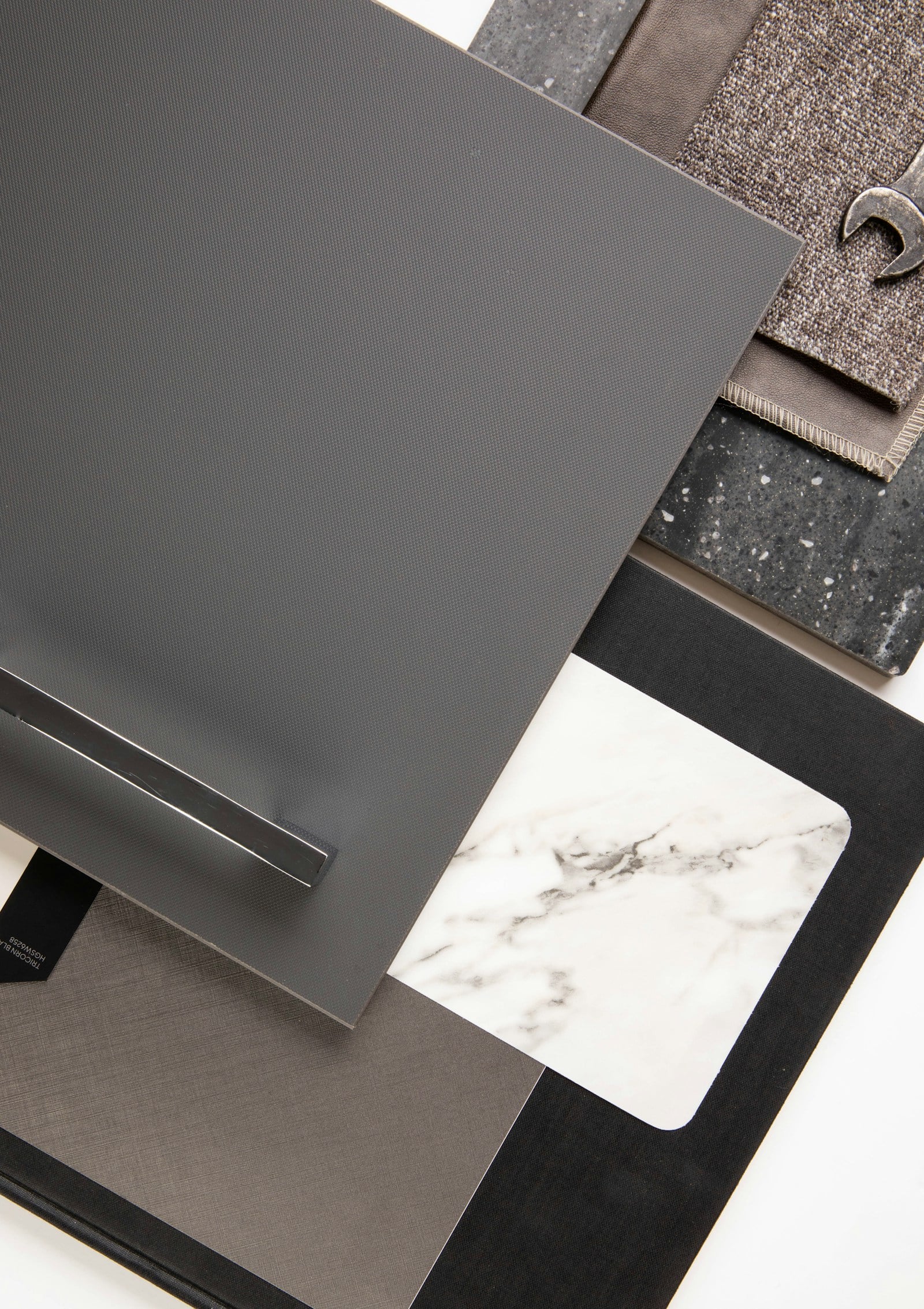 Close-up of cabinet finish samples in grey, marble and fabric, with a slim bar handle