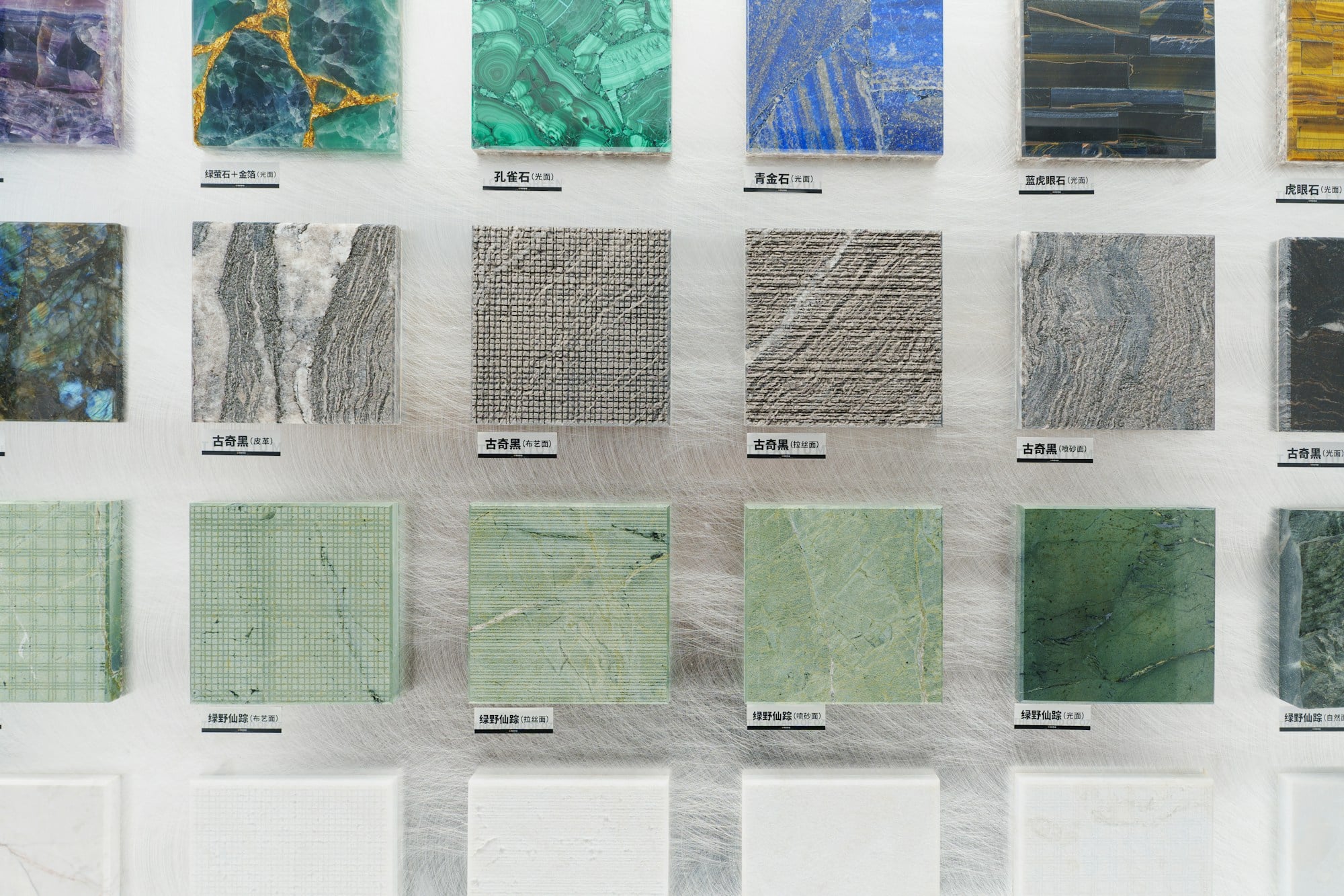 Wall display of polished stone and textured finish samples in green, grey and blue tones